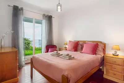 a bedroom with a bed with pink pillows and a window at Blissful Haven - Soulful Stays in Porto Moniz