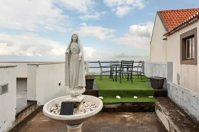 a statue sitting on the balcony of a house at Blissful Haven - Soulful Stays in Porto Moniz