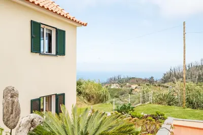 a white house with green shutters and a garden at Palheiro Simone by Homie in Lanceiros