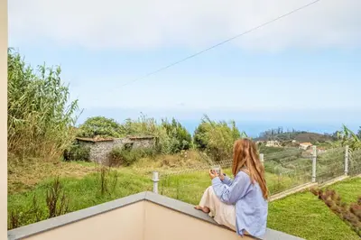 a woman sitting on a ledge looking out at the ocean at Palheiro Simone by Homie in Lanceiros