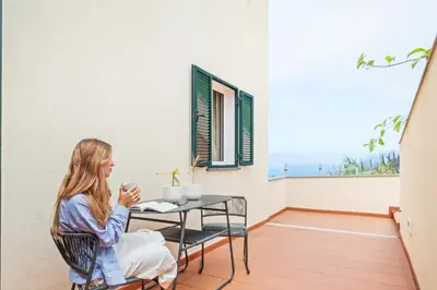 a woman sitting at a table on a balcony at Palheiro Simone by Homie in Lanceiros