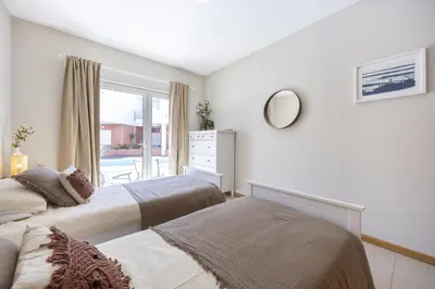a white bedroom with two beds and a window at Casa do Mar in Burgau