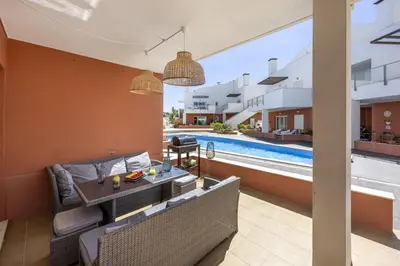 a patio with a table and chairs and a swimming pool at Casa do Mar in Burgau