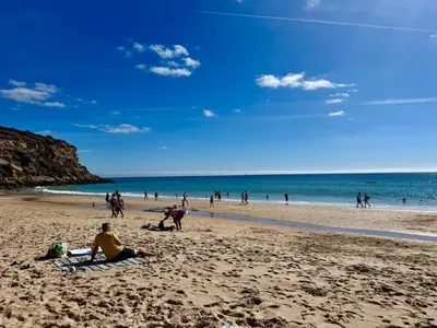 a group of people sitting on a beach at Casa do Mar in Burgau