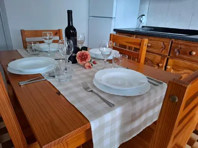 a kitchen with a table and a white refrigerator at Varanda Encantada House in Ponta do Sol