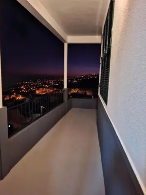 a balcony with a view of the city at night at Varanda Encantada House in Ponta do Sol