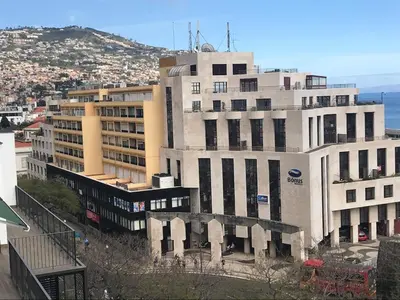 a tall white building next to the ocean at Top Floor Apartment 805 in Funchal