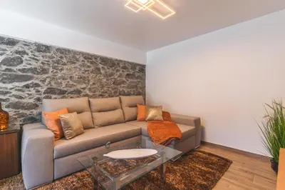 a living room with a couch and a stone wall at Julianas House 2 by Atlantic Holiday in Campanário