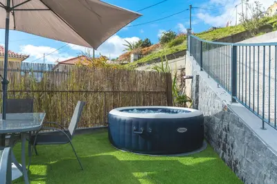 a hot tub in a yard with a table and an umbrella at Julianas House 2 by Atlantic Holiday in Campanário