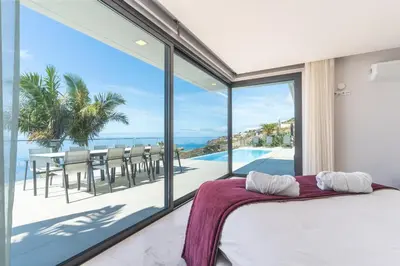 a bedroom with a bed and a view of the ocean at Villa Zenha by Atlantic Holiday in Ribeira Brava