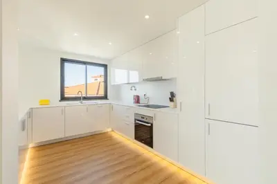a kitchen with white cabinets and a wooden floor at Garajau Sea Side by Atlantic Holiday in Caniço