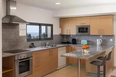 a kitchen with wooden cabinets and a granite counter top at MarAnteMar by An Island Apart in Porto Santo