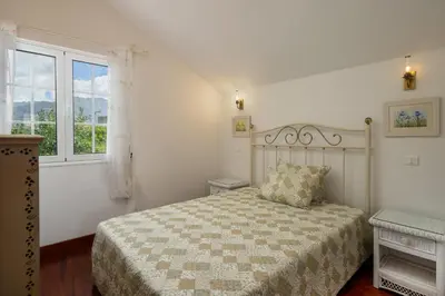 a white bedroom with a bed and a window at Casa da Avo in Faial