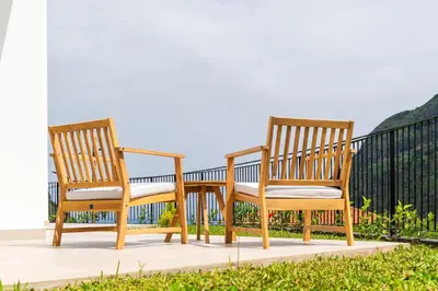 two wooden chairs sitting on a balcony at Elysium São Vicente - Designer Villa with Ocean View, Heated Pool, Jacuzzi & Sauna in São Vicente