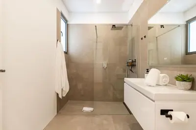 a white bathroom with a shower and a sink at Elysium São Vicente - Designer Villa with Ocean View, Heated Pool, Jacuzzi & Sauna in São Vicente