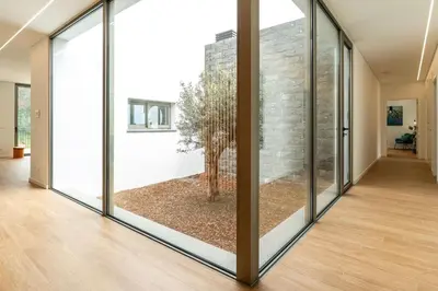 a hallway with sliding glass doors with a tree inside at Elysium São Vicente - Designer Villa with Ocean View, Heated Pool, Jacuzzi & Sauna in São Vicente