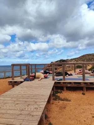 a group of people laying on yoga mats on a pier at Casa Fidal in Bordeira