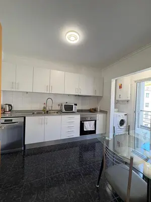 a kitchen with white cabinets and a glass table at Island Heart- Family Retreat- Free parking garage in Ribeira Brava