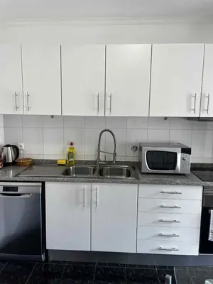 a kitchen with white cabinets and a sink and a microwave at Island Heart- Family Retreat- Free parking garage in Ribeira Brava