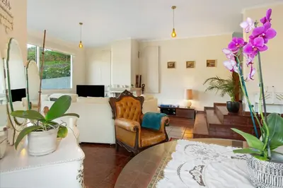 a living room with a chair and a table with purple flowers at Traveller's House in Machico