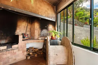 an outdoor kitchen with a pizza oven and windows at Traveller's House in Machico
