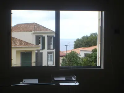 a window with a view of a building and a house at Shearwaternest Apartment AL in Funchal