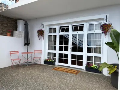a patio with a door and two chairs and an umbrella at Airport Oasis in Santa Cruz