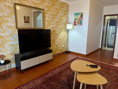 a living room with a television and a table and a mirror at Airport Oasis in Santa Cruz