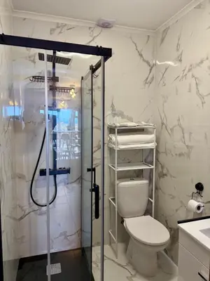 a bathroom with a toilet and a glass shower at Airport Oasis in Santa Cruz