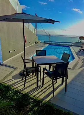 a table and chairs and an umbrella next to a swimming pool at A&M House III in Arco da Calheta