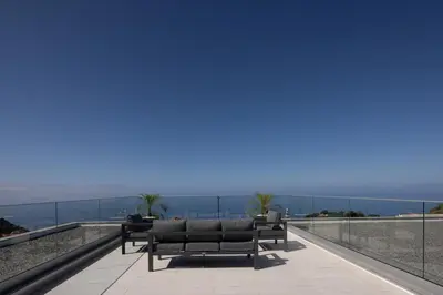 a row of benches on a balcony with a view of the ocean at A&M House III in Arco da Calheta