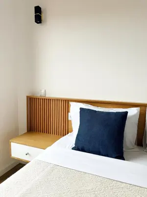 a bed with a blue pillow and a wooden headboard at S A L - Village Flats in Caniçal