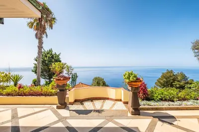 a garden with a bench with plants and the ocean in the background at PRIVATE OCEANFRONT DELUXE VILLA PICO 360 VIEWs in Funchal