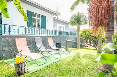 two chairs and a table in the yard of a house at Villa Por do Sol in Ponta do Sol
