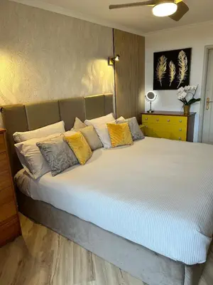 a large bed with yellow and white pillows on it at Jardim do Caniço in Caniço