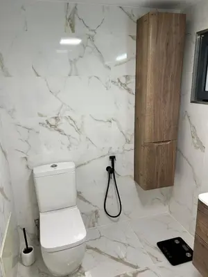 a white bathroom with a toilet and a shower at Jardim do Caniço in Caniço
