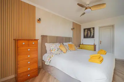 a bedroom with a bed and a dresser with yellow towels on it at Jardim do Caniço in Caniço