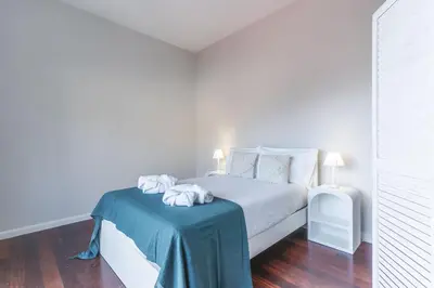 a white bedroom with a bed with a blue table at Casa dos Namora by Atlantic Holiday in Câmara de Lobos