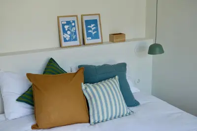 a white bed with blue and white pillows on it at Araça Studio - Atlantic Mountain Living in São Vicente