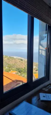 a window with a view of a field and the ocean at Refúgio das Regadinhas in Santa Cruz