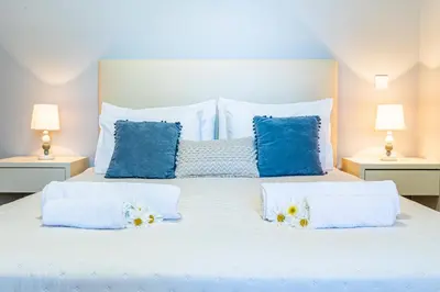 a bedroom with a white bed with blue pillows at Estrela house II Calheta Madeira in Calheta