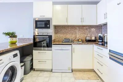 a kitchen with white cabinets and a washer and dryer at Estrela house II Calheta Madeira in Calheta
