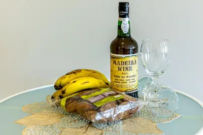 a bottle of wine and a bunch of bananas on a table at Estrela house II Calheta Madeira in Calheta