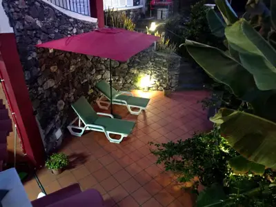 an umbrella and chairs on a patio at night at Apart Monumental in Funchal