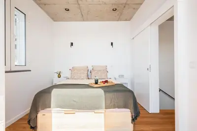 a white bedroom with a large bed with a wooden platform at The Vinehill House in Câmara de Lobos