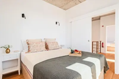a white bedroom with a bed with a gray blanket at The Vinehill House in Câmara de Lobos