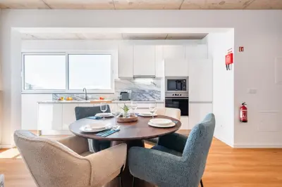 a kitchen and dining room with a wooden table and chairs at The Vinehill House in Câmara de Lobos