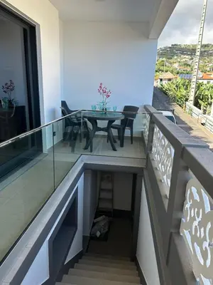 a balcony with a glass table and chairs on it at Refúgio Ponta do Sol - Madeira Inn Group in Ponta do Sol
