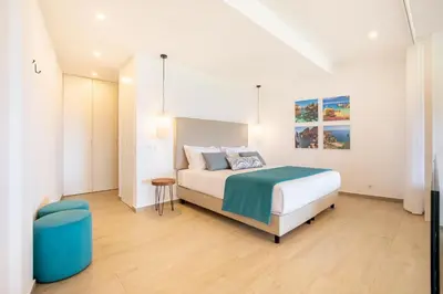 a white bedroom with a bed and a blue stool at The Oceanfront Studio Luz VR110 in Luz