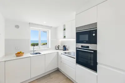 a white kitchen with white cabinets and a window at The Oceanfront Studio Luz VR110 in Luz